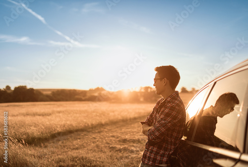 Young thoughtful man smiling looking out to the sunset feeling grateful, and happy in nature 