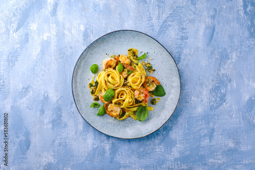 Traditional Italian tagliatelle ai gamberoni pasta with king prawns and herbs served as top view on a design plate with copy space photo