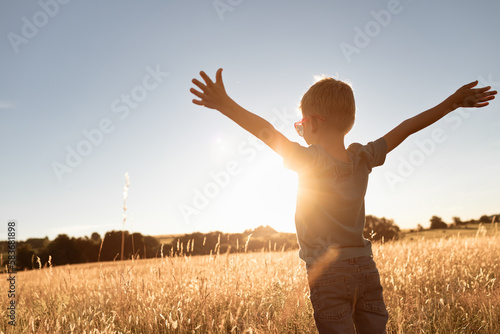 Slika na platnu It's a beautiful life! Child standing with arms up facing the sunrise having fee