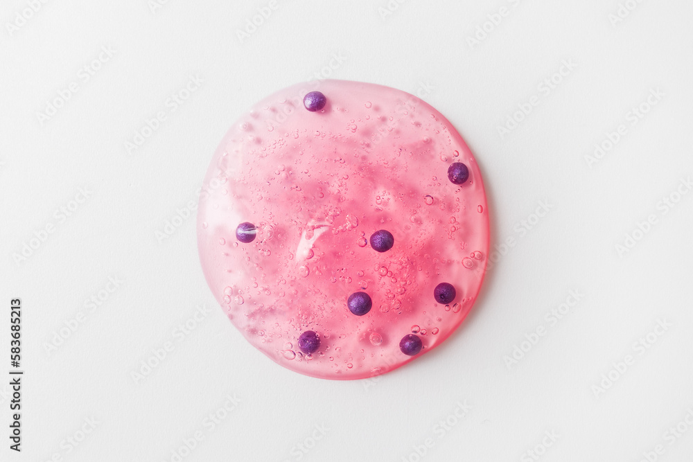 Round drop of pink gel scrub with bubbles on white background. Concept of skin care and exfoliation. Backdrop for skincare product. Selective focus