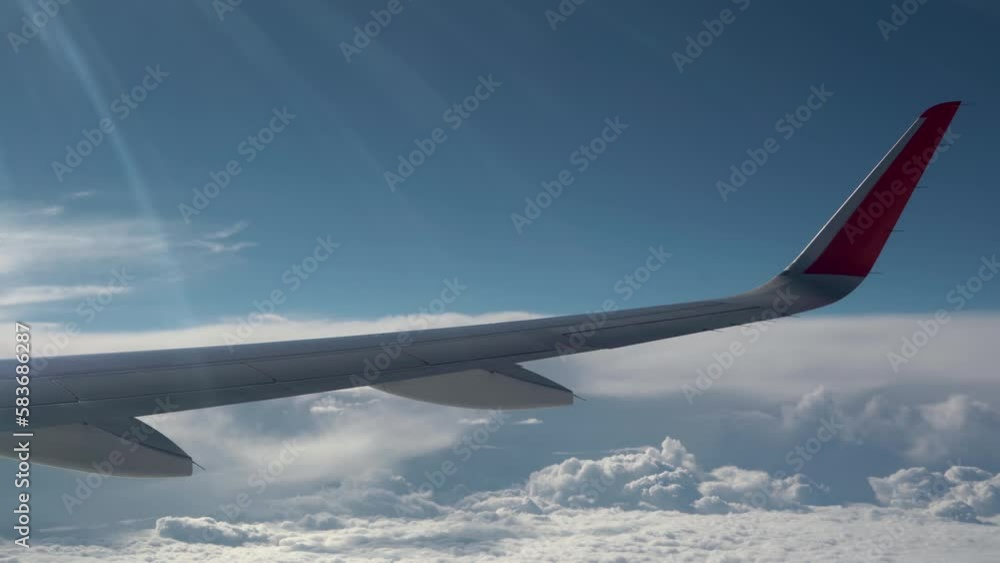 Wing of aircraft flies over clouds. Sun rays on wing. Small clouds fly fast Wing of aircraft flies over clouds. Sun rays on wing. Small clouds fly fast