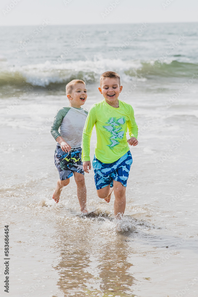 Boys playing and running in the ocean water in the sunshine