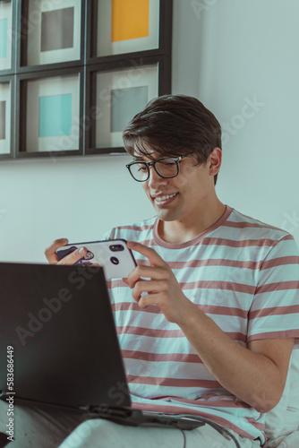 joven usando el celular y laptop 