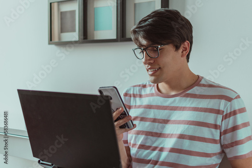 joven usando el celular y laptop 