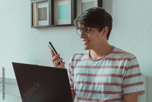 hombre joven hablando por celular en frente del laptop 
