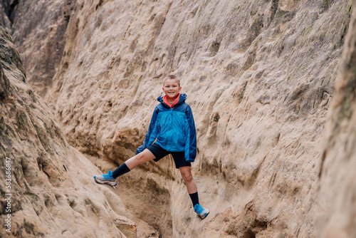Boy hiking climbing through a sandstone slot canyon