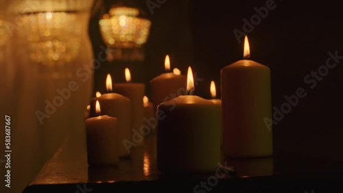 Black candles cast an eerie glow on the dark background as a witch performs a magic ritual with voodoo and paganism. A close-up reveals the intensity of the mystic rite