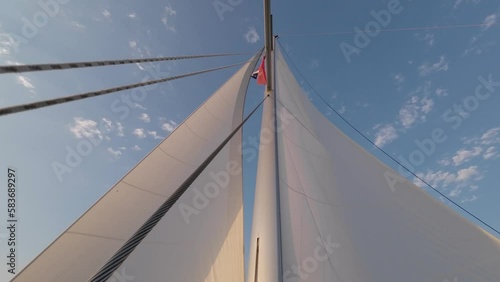 4K Sailboat Mast and Sail. Open, unfurled sails on a yacht. Sailing in the wind. Full sails, very strong wind. Lens Flare Light Leak Wind Power. Sun sails and sunset Sunlight photo