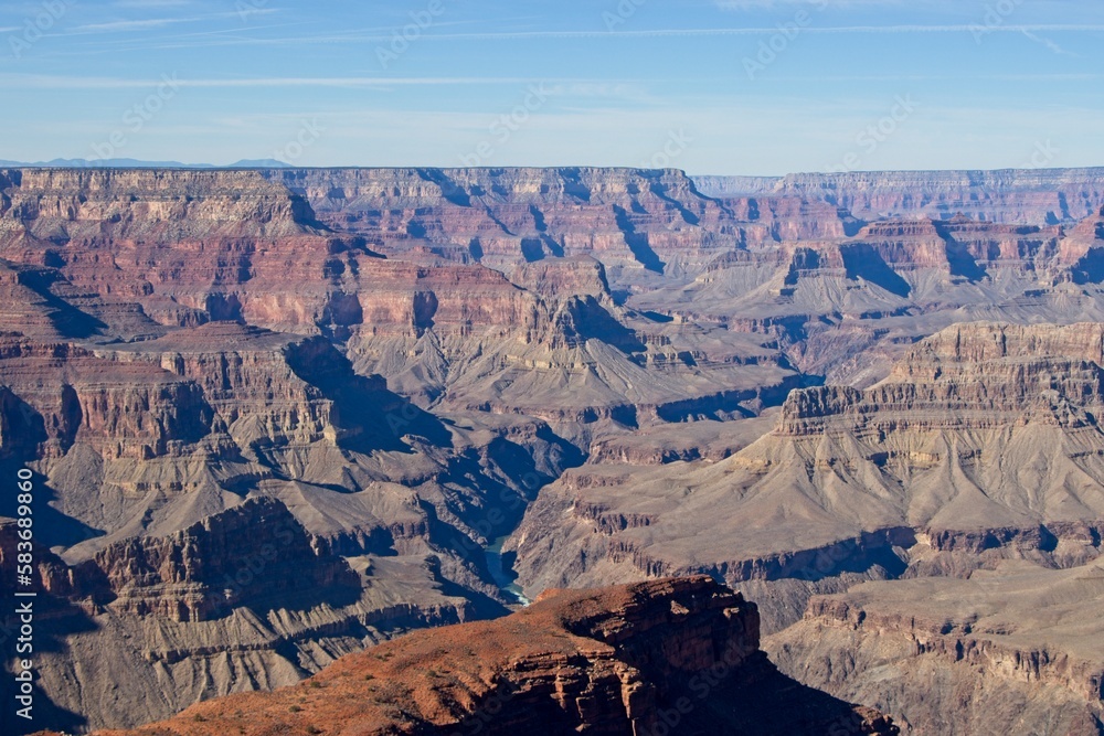 Bright desert sunlight shines down on the Grand Canyon, casting shadows on every crease and layer of the eroded canyon carved over many years by the Colorado River thousands of feet below Bright desert sunlight shines down on the Grand Canyon, casting shadows on every crease and layer of the eroded canyon carved over many years by the Colorado River thousands of feet below