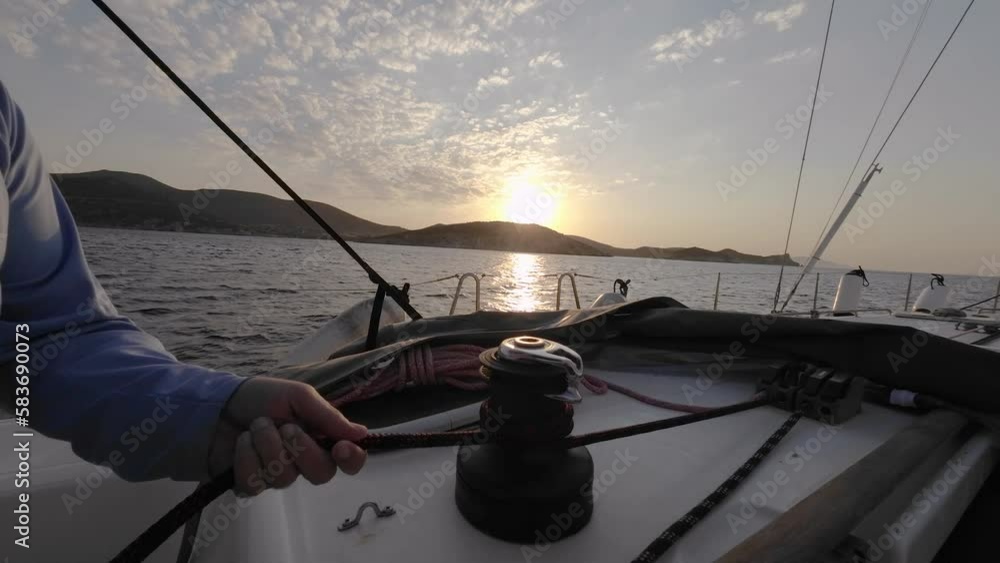 Sailor's hand on a winch of sailing boat against the sunset. Man