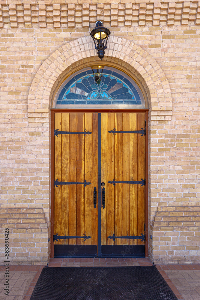 Double wooded entry doors with a stained glass arched transom at