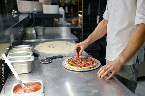 Bild auf Leinwand Pizzaiolo making pizza at kitchen with closeup focus on hand