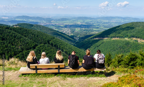 Group of people sitting on a bench enjoying the views after a challenging hike. Beautiful nature