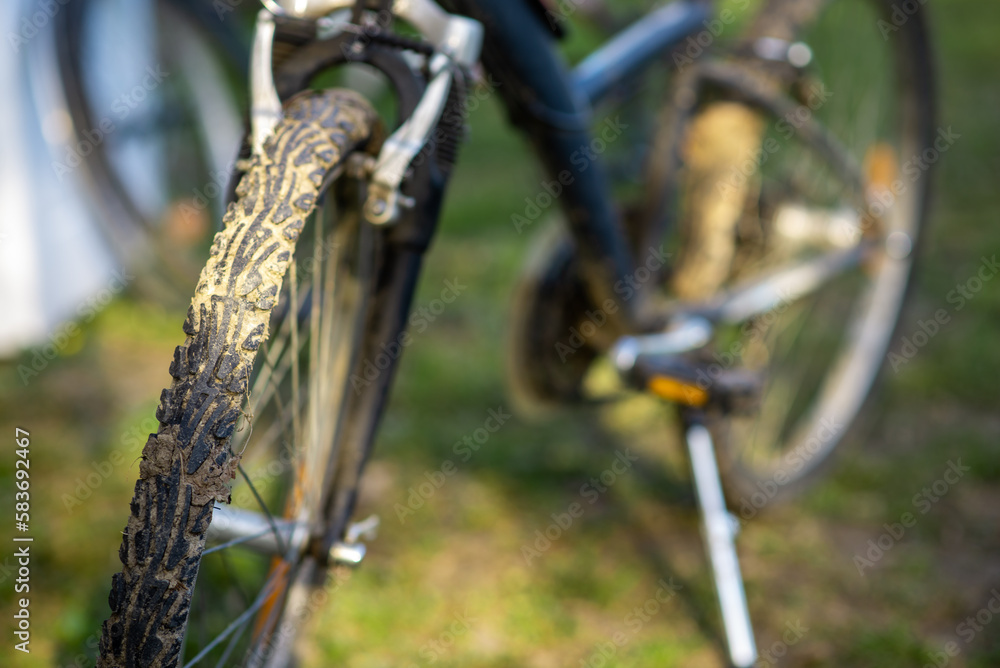 Dirty bike wheel. Bicycle rides, travel, outdoor activities. The bike is on the green grass. Dirty bike wheel. Bicycle rides, travel, outdoor activities. The bike is on the green grass.