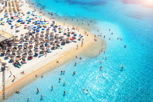 Aerial view of colorful umbrellas on beach, people in blue sea photo