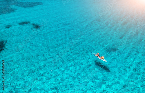 Aerial view of kayak with people in blue sea at sunset in summer