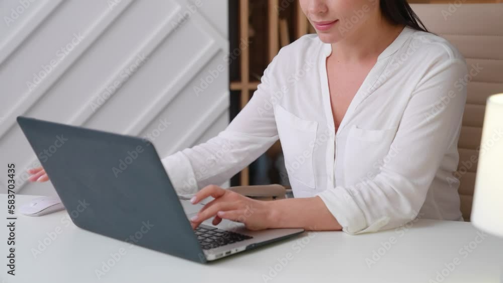Young female freelancer in a white blouse works at home on a modern laptop. Young business woman worker in the office typing on a laptop close-up Young female freelancer in a white blouse works at home on a modern laptop. Young business woman worker in the office typing on a laptop close-up