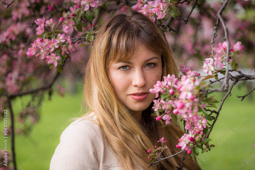 Spring portrait of a beautiful caucasian woman standing beside a tree in bloom. She has blonde hair and blue eyes. She is at a local park. Spring portrait of a beautiful caucasian woman standing beside a tree in bloom. She has blonde hair and blue eyes. She is at a local park.