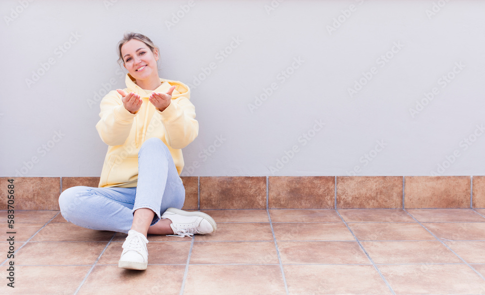 pretty caucasian sitting  woman smiling happily with friendly, confident, positive look, offering and showing an object or concept