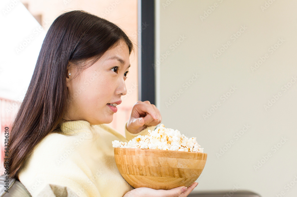 asian pretty woman eating popcorns and watching a film at home asian pretty woman eating popcorns and watching a film at home