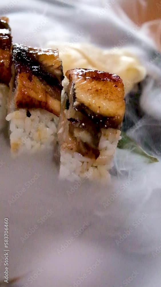 food court restaurant serving Japan Asia sushi with eel is served on palm leaf white ginger marinated with dry ice steam slowly spreads on a black stone plate tasty beautiful aesthetic Japan China food court restaurant serving Japan Asia sushi with eel is served on palm leaf white ginger marinated with dry ice steam slowly spreads on a black stone plate tasty beautiful aesthetic Japan China