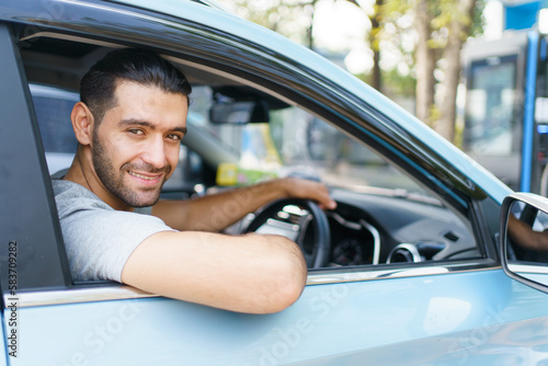 Happy cheerful Asian ale car driver waving or showing thumb up and smiling out of the car.  © DG PhotoStock