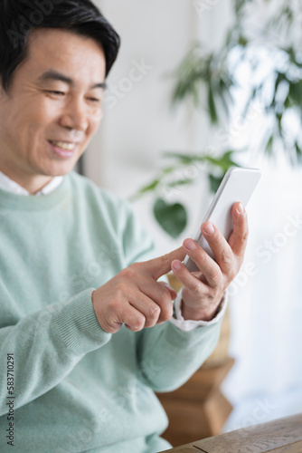 自宅でスマートフォンを使う50代男性