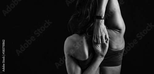 Sporty healthy body woman with strong muscular shoulders and blades doing hands the lock exercise behind the back on black background. Closeup studio portrait