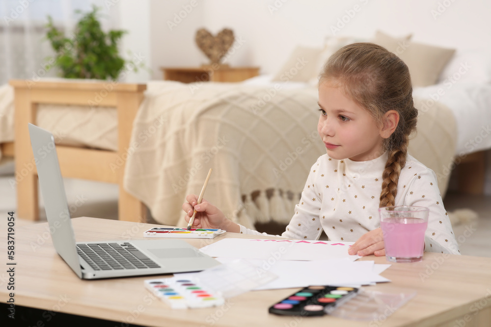 Little girl learning to paint with online course at home. Space for text Little girl learning to paint with online course at home. Space for text