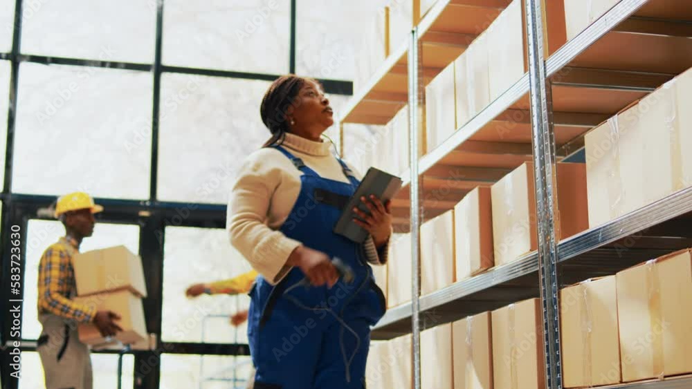 Woman working with scanner and tablet in storage room, scanning cardboard packages with barcodes in depot. Female worker checking boxes with merchandise and products, quality control. Handheld shot. Woman working with scanner and tablet in storage room, scanning cardboard packages with barcodes in depot. Female worker checking boxes with merchandise and products, quality control. Handheld shot.