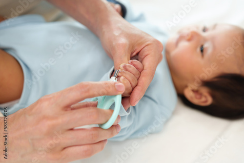 mother cutting baby's hand fingernails with nail scissors.