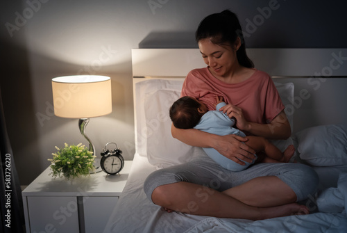 Fotografía mother breastfeeding newborm baby on bed at night