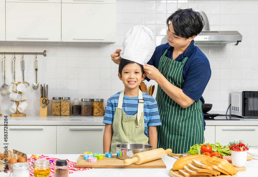 Adorable son doing cooking training in kitchen room. Adorable son doing cooking training in kitchen room.