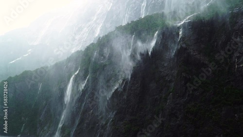 Fantasy waterfalls on rocks of Milford Sound, New Zealand on heavy rain blown by wind