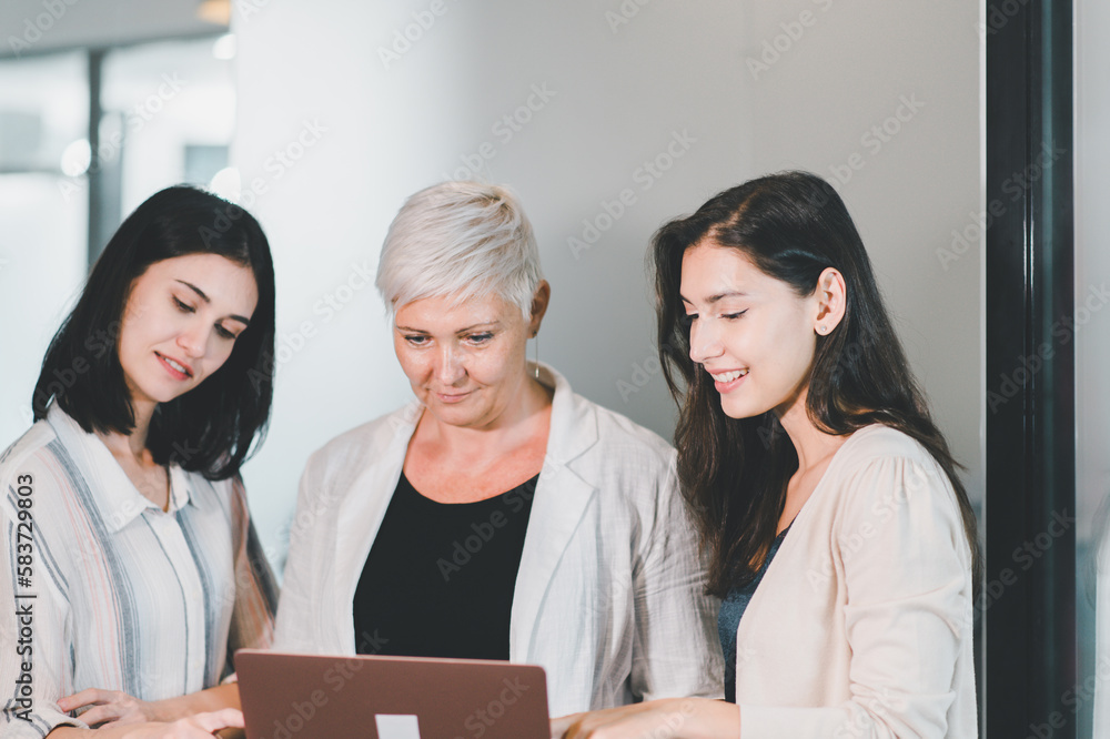 Teamwork of woman copywriter in casual suit working with laptop in modern office together Teamwork of woman copywriter in casual suit working with laptop in modern office together