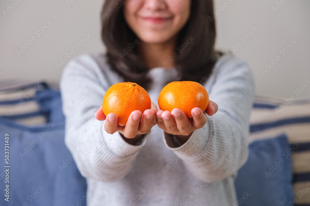 Closeup image of a young woman holding oranges in hands Closeup image of a young woman holding oranges in hands