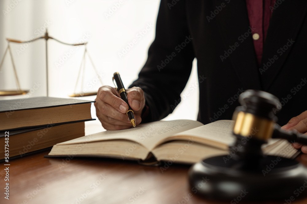 female lawyer, law adviser, businesswoman sitting and reading with finger pointing at legal code information. Business agreement on book working with scales and hammer in office. female lawyer, law adviser, businesswoman sitting and reading with finger pointing at legal code information. Business agreement on book working with scales and hammer in office.