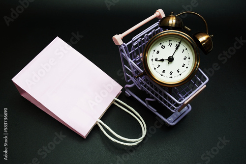 Trolley cart and shopping bag with alram clock with space copy on black background photo