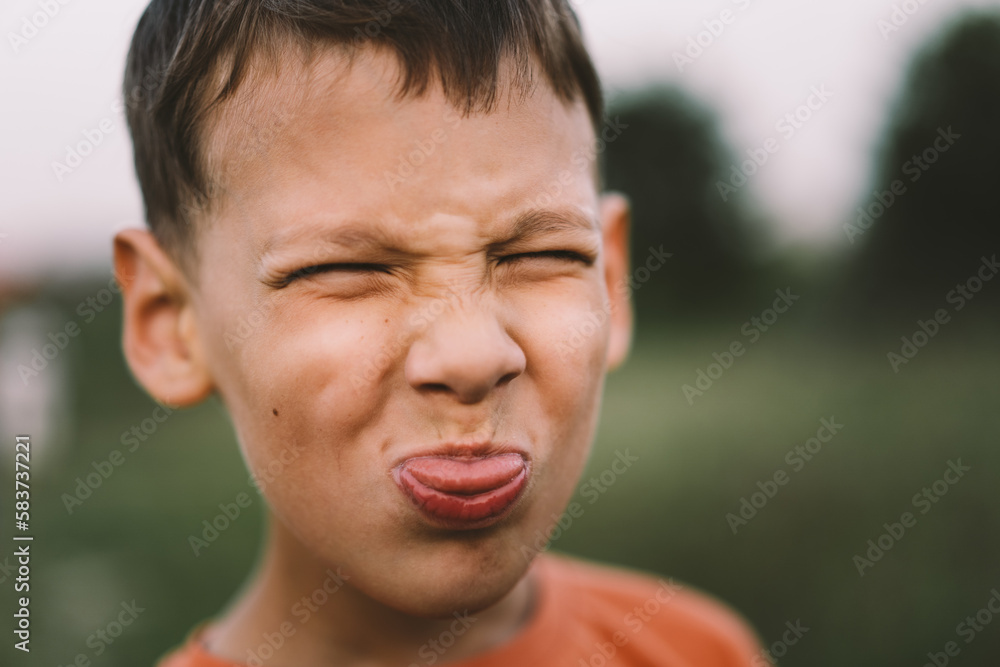 Portrait of a funny boy in a orange T-shirt and playing outdoors on the field at sunset. Happy child, lifestyle. Portrait of a funny boy in a orange T-shirt and playing outdoors on the field at sunset. Happy child, lifestyle.