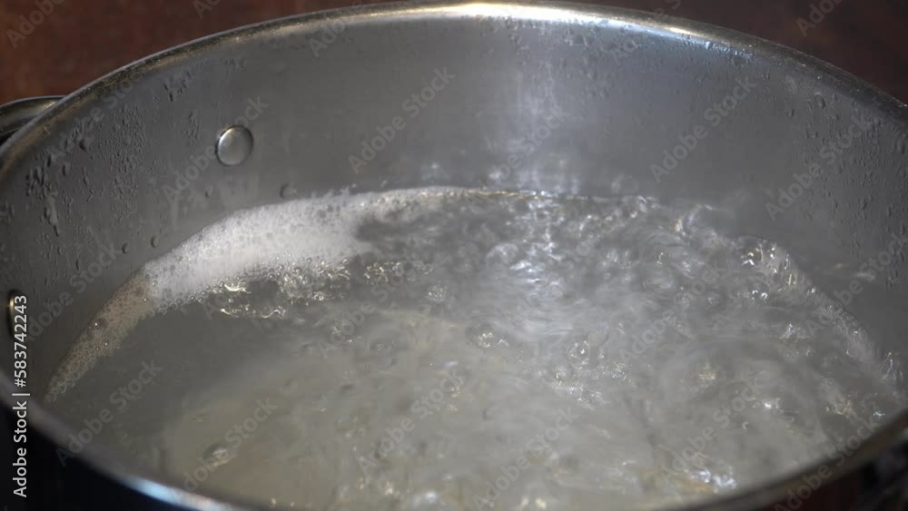 Boiling rice in portion bag. A bag of white, cooked rice is held with a hand in front of a dark background. Boiling rice in portion bag. A bag of white, cooked rice is held with a hand in front of a dark background.