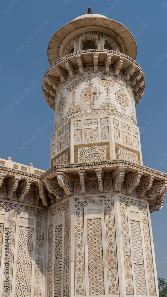 Details of the architecture of the ancient tomb of Itmad-Ud-Daulah.  The marble minaret is decorated with carvings, ornaments, inlays of precious stones. Blue sky. India. Agra