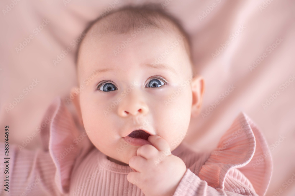Portrait of a blue-eyed 6 months baby girl with finger in mouth Portrait of a blue-eyed 6 months baby girl with finger in mouth