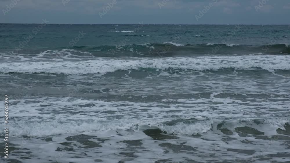 Slow motion of foamy waves falling towards sand beach under low the sunlight Slow motion of foamy waves falling towards sand beach under low the sunlight