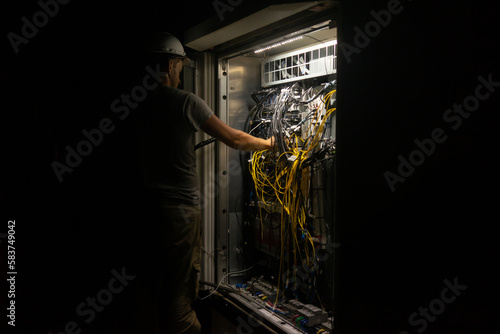 Electrical technician working in a switchboard of cell tower try to fix defect. 