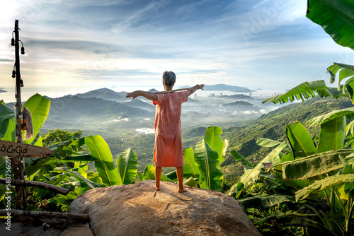 An elderly woman meditates in the morning in the mountains of Nha Trang. Looking in the distance is the coastal city of Nha Trang, Khanh Hoa province, Vietnam photo