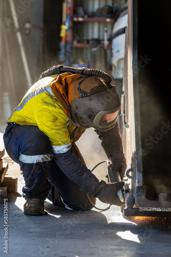 Angle grinding to repair an excavator's bucket inside a factory