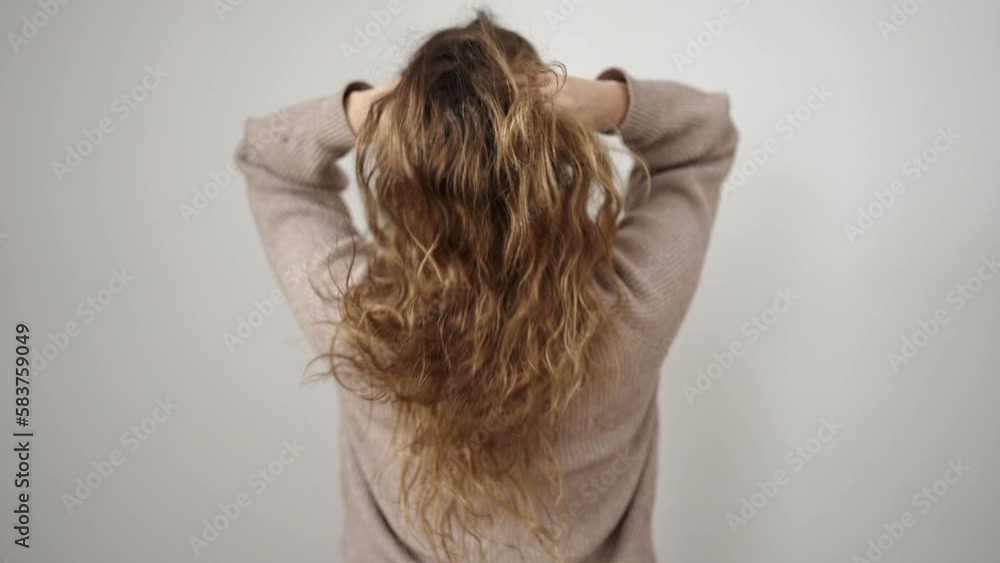 Young beautiful hispanic woman combing hair with hands on back view over isolated white background Young beautiful hispanic woman combing hair with hands on back view over isolated white background