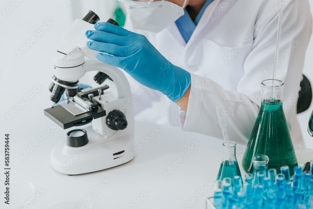Scientist or doctor wear medical protective mask looking at blood samples under microscope. Scientist or doctor wear medical protective mask looking at blood samples under microscope.