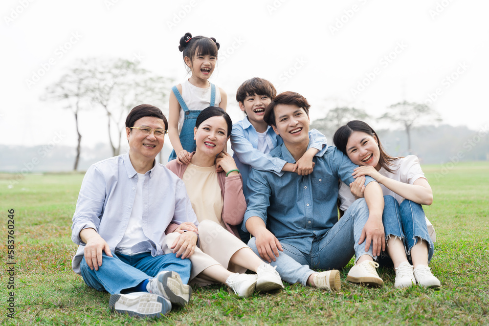 image of an asian family sitting together on the grass at the park image of an asian family sitting together on the grass at the park