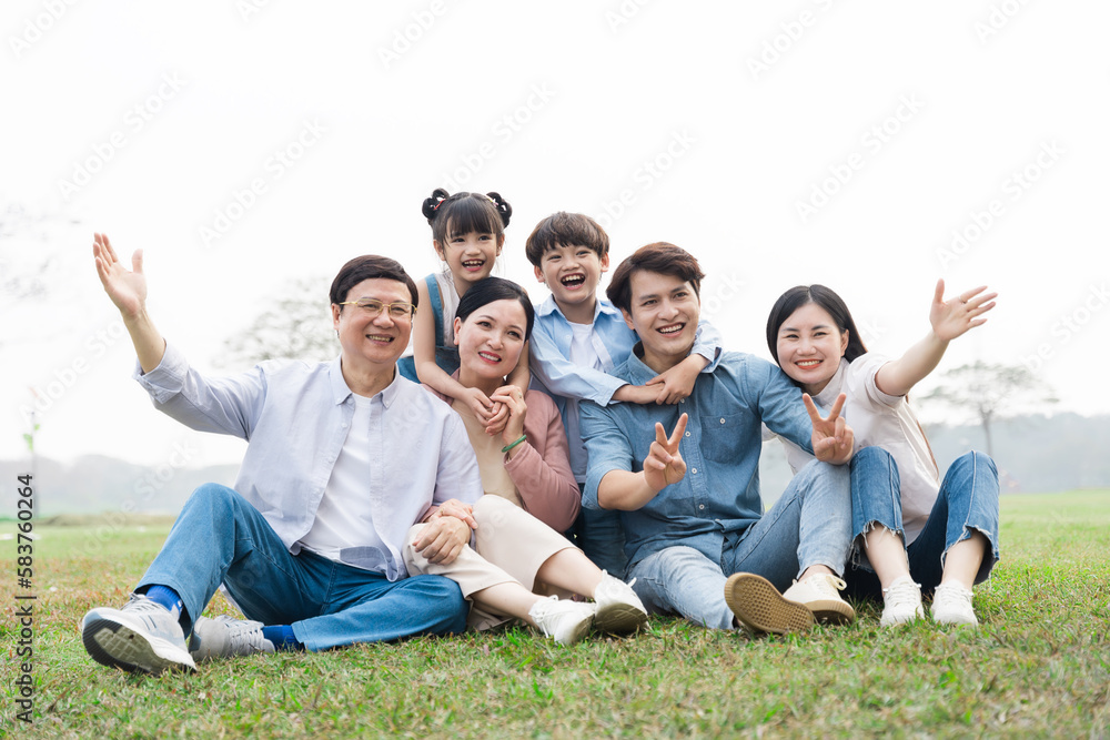 image of an asian family sitting together on the grass at the park image of an asian family sitting together on the grass at the park